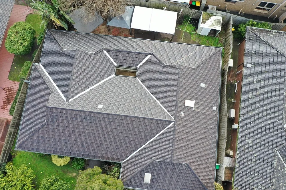 After: the same concrete tiled roof restored with a charcoal membrane coating