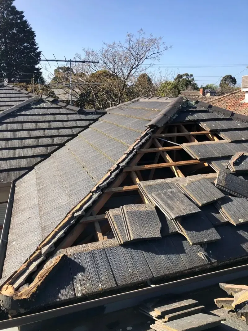 Before: concrete tiles and ridge capping torn off, exposing the roof frame