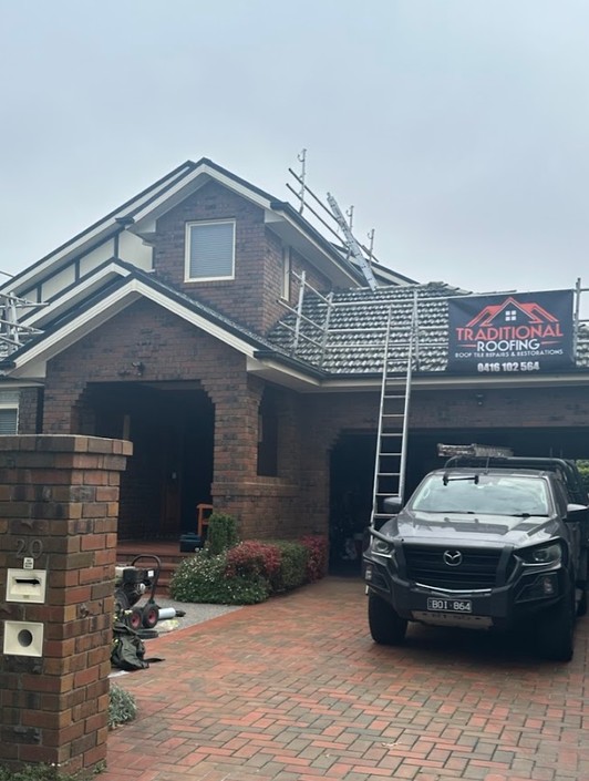 Traditional Roofing job site with the company banner on the edge protection and the work ute in the driveway