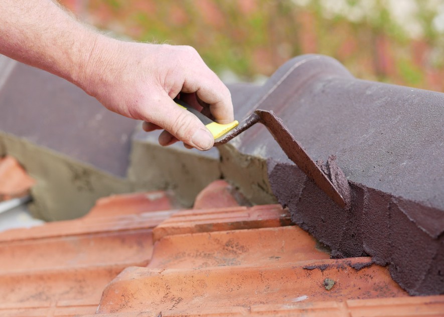 Close-up of flexible pointing being trowelled onto terracotta ridge capping