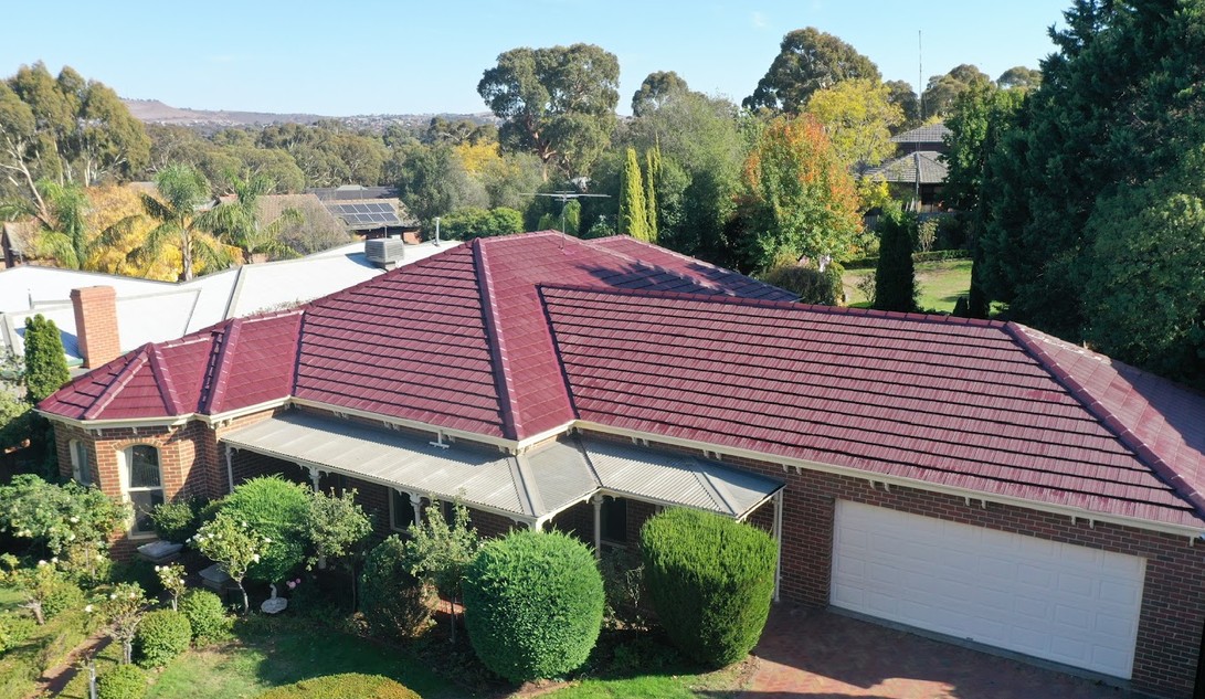 Drone view of a restored red tiled roof on a brick home