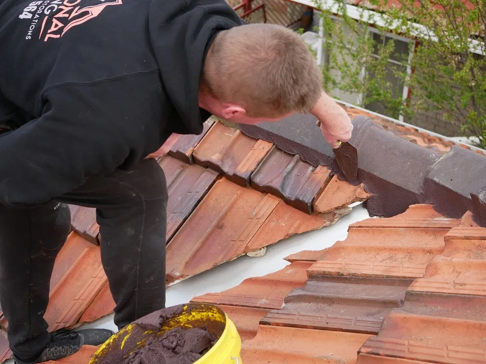 Traditional Roofing team member applying flexible pointing to terracotta ridge capping