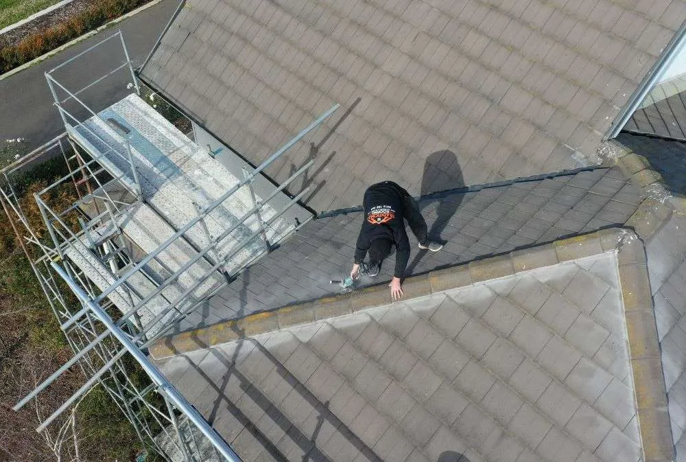 Drone view of a Traditional Roofing roofer working along a ridge line with edge protection in place