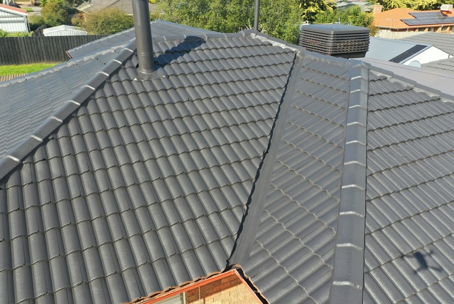 Restored charcoal concrete tiled roof with neat ridge and hip capping