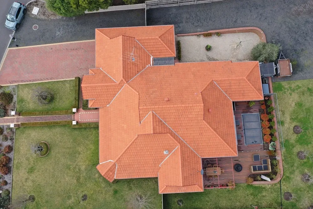 Top-down drone view of a terracotta tiled roof with hips and valleys